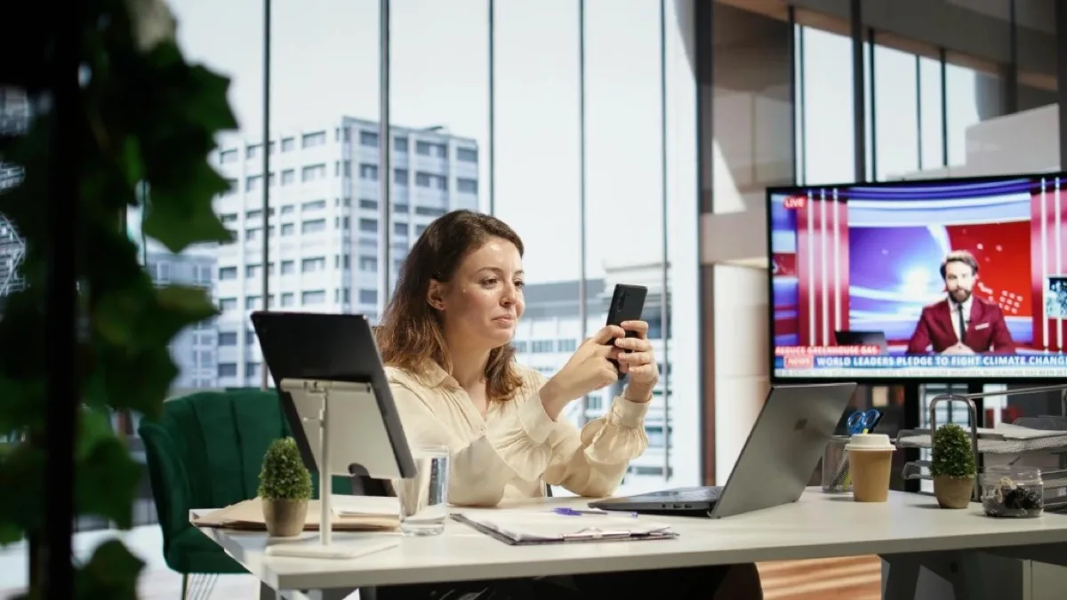 Geschäftsfrau in einem modernen Büro nutzt Smartphone und Laptop für Social-Media-Kommunikation